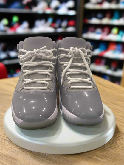 Gray high-top sneakers with white laces on a white platform.