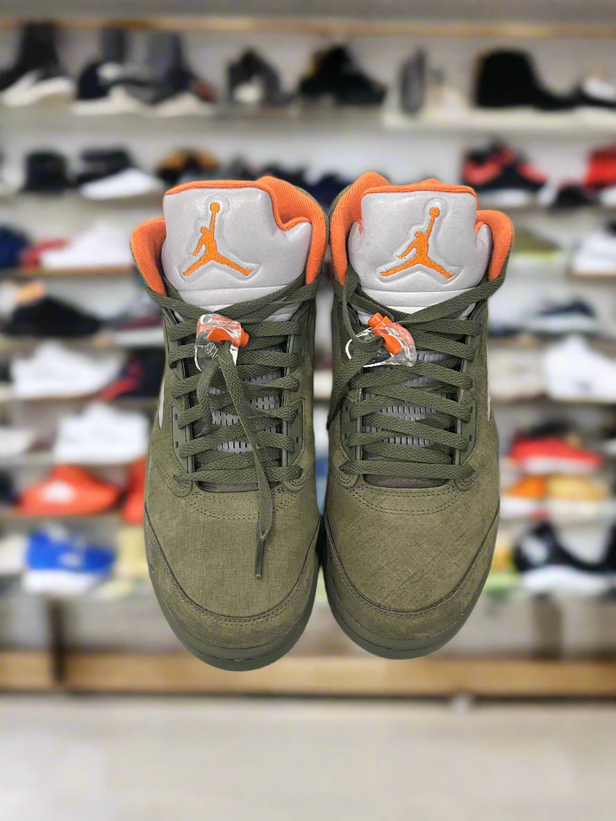 Green sneakers with orange accents on a blurred shoe store background